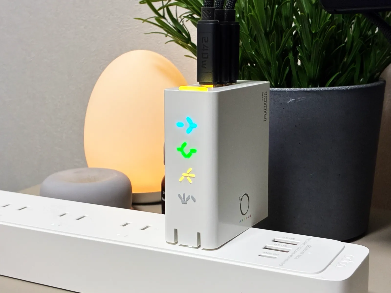 電源タップに挿したPHYSCE 100Wに、ケーブルを3本つないで充電しているところ。上面のライトは黄色、側面に並んだ文字は青・緑・黄色に光っている