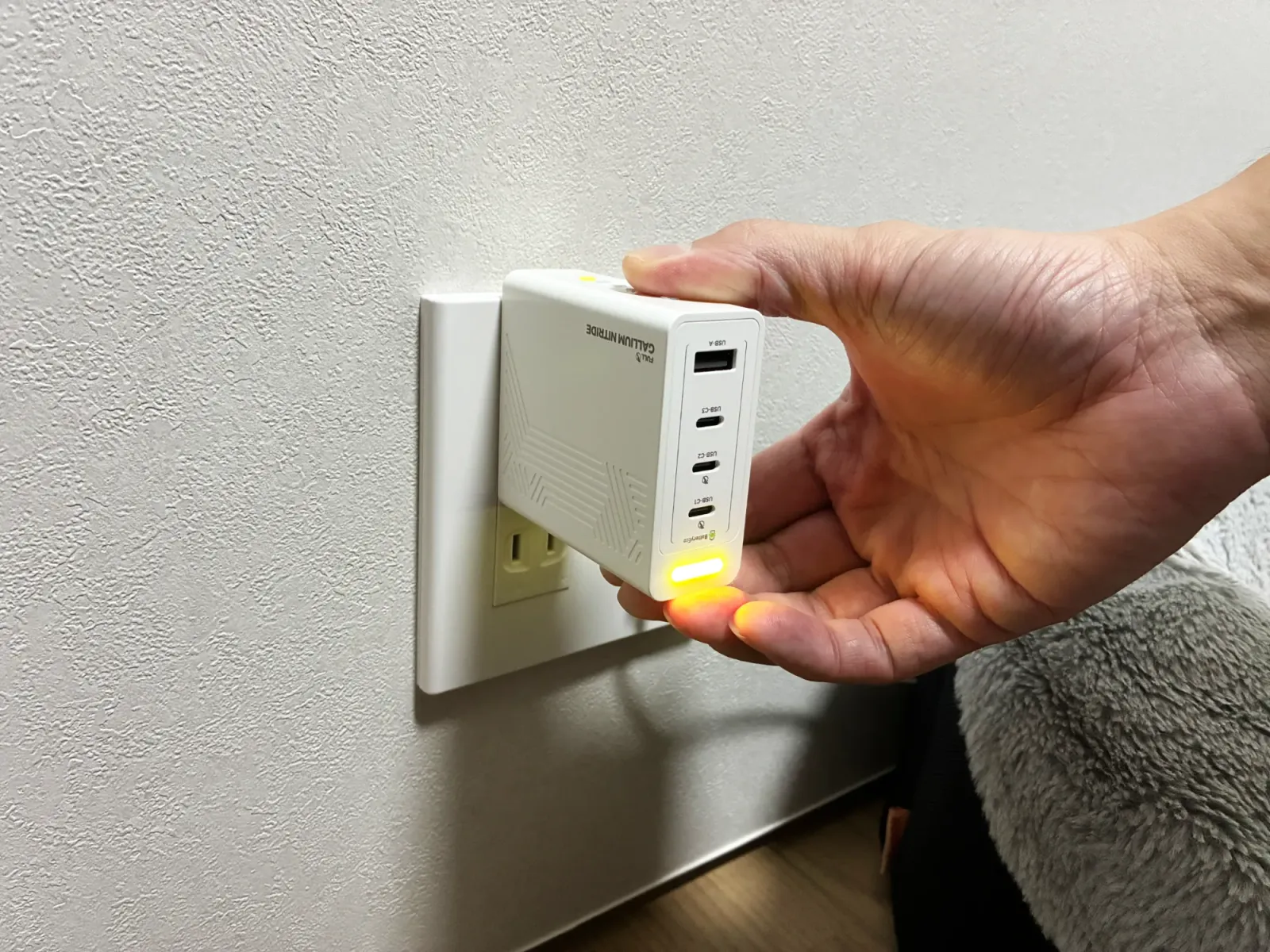 壁のコンセントの上の差込口にPHYSCE 100Wを挿したところ。本体が壁から大きく出っ張っている